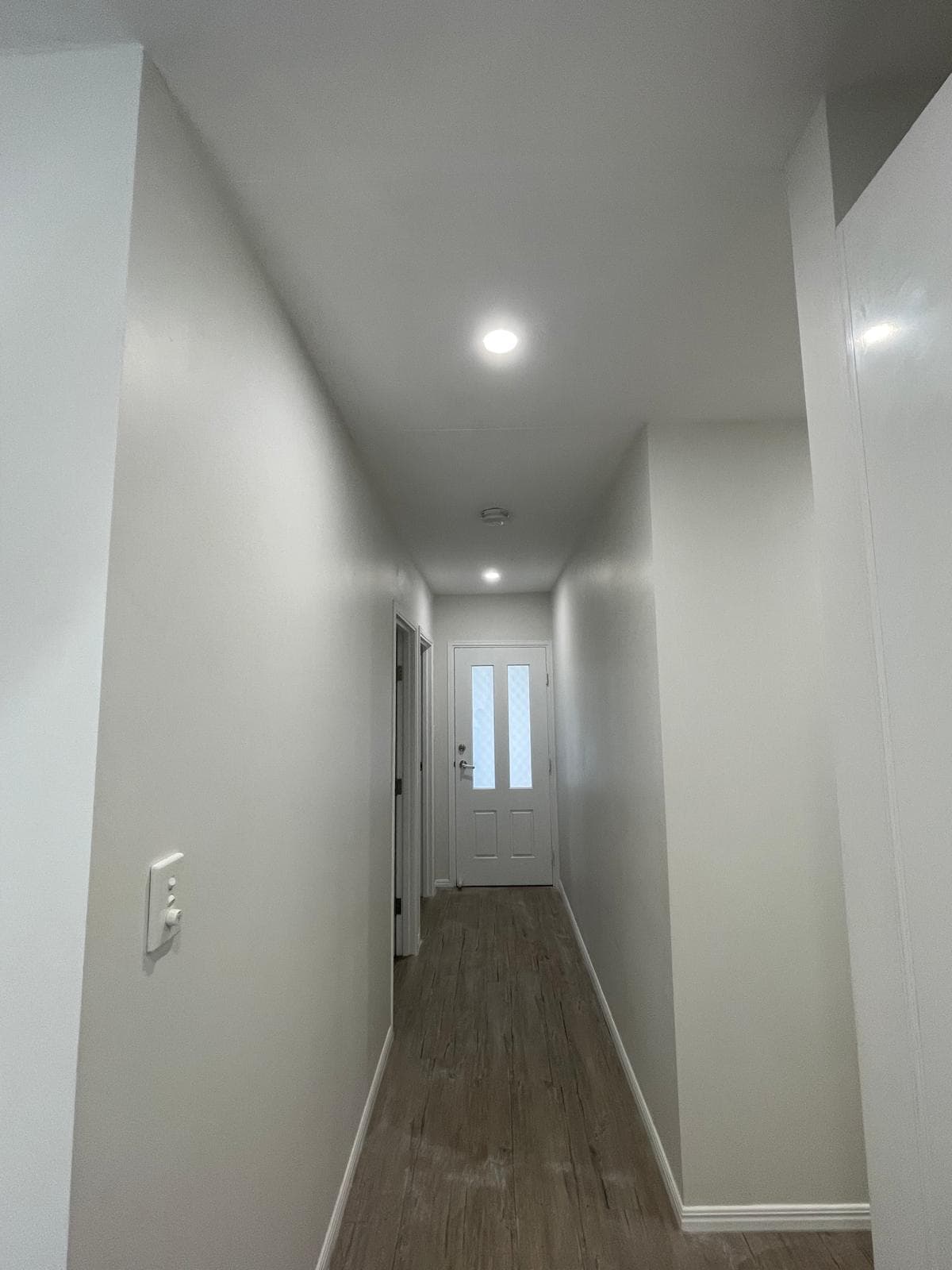 Freshly painted hallway with recessed lighting and light timber floors