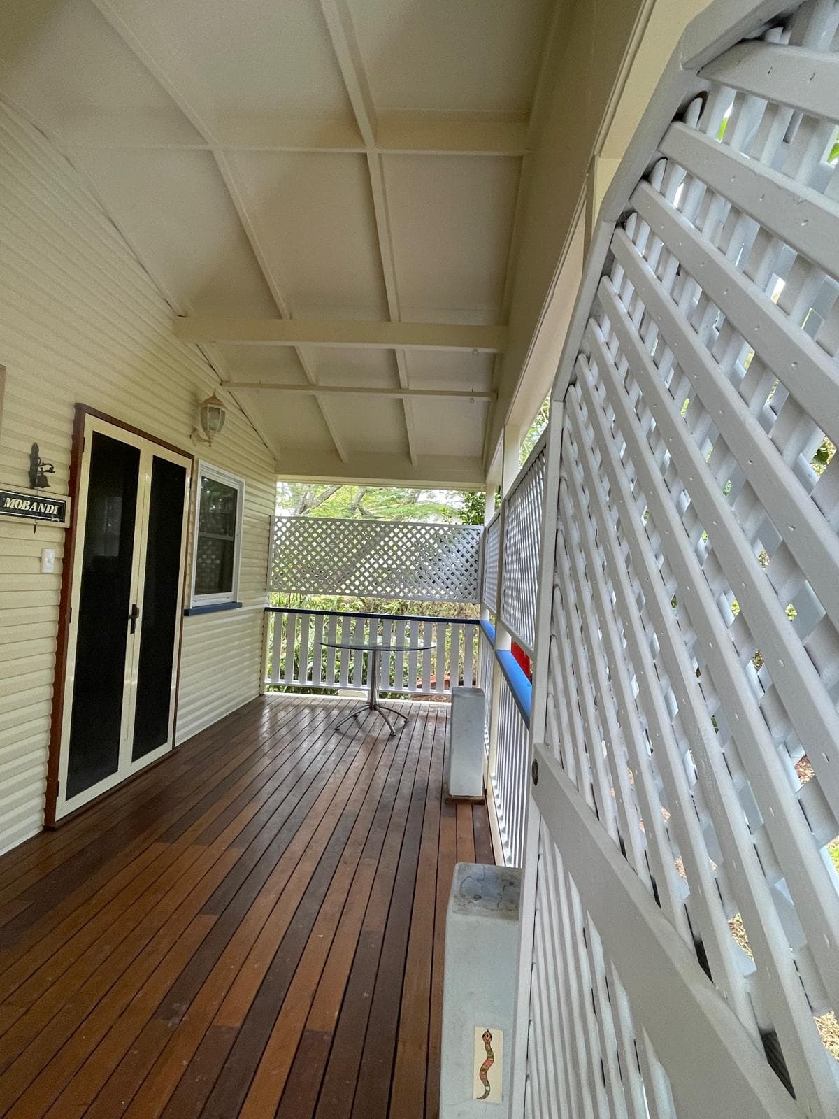 Polished timber porch with white lattice screens and navy handrail